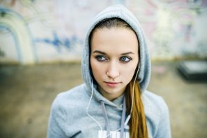 Teenage girl with hood on listening to music